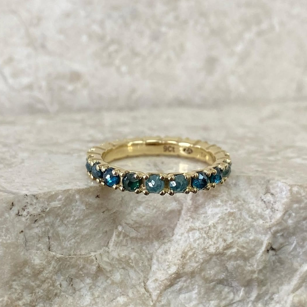 Gold ring with blue gemstones on a textured stone surface
