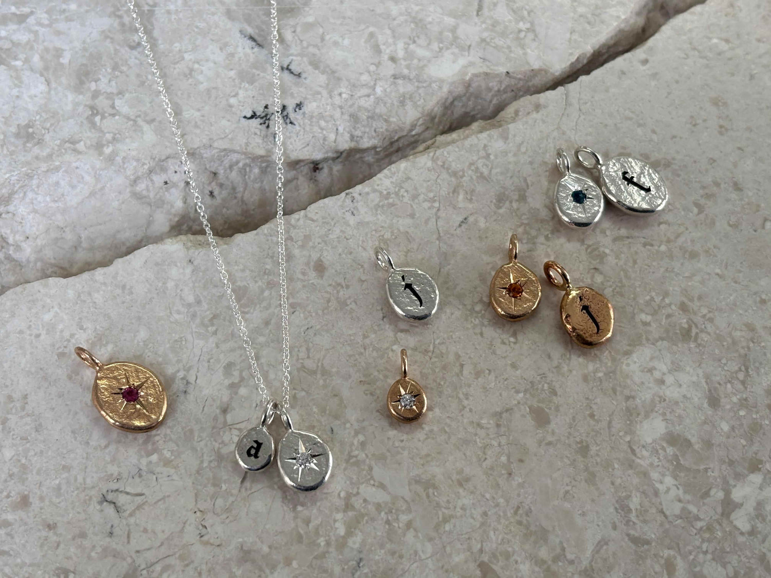 Collection of story pendants by Tiffany Marx in silver and bronze gothic letters and birthstones